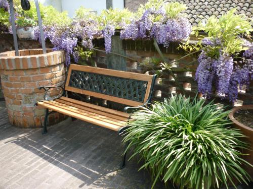 a wooden bench in a garden with purple flowers at Bed And Breakfast Olimpia in San Salvatore Monferrato