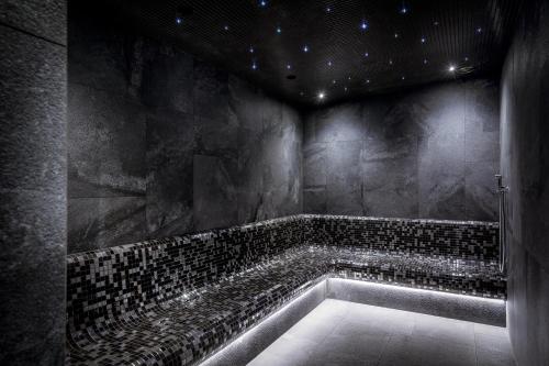 a dark bathroom with a tub with black tiles at Lake Hill Karkonosze Resort & Spa in Sosnówka
