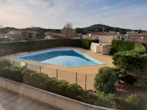 ein großer Pool in einem Garten mit einem Zaun in der Unterkunft Studio Port Vénus Village Naturiste in Cap d'Agde