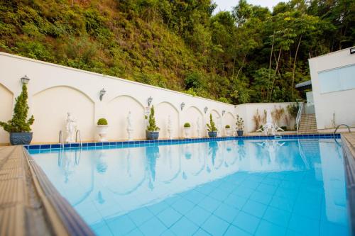 uma piscina num hotel com árvores ao fundo em Hotel Himmelblau em Blumenau