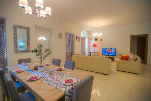 a dining room with a long table and a living room at Santalas Villa in Ágios Matthaíos