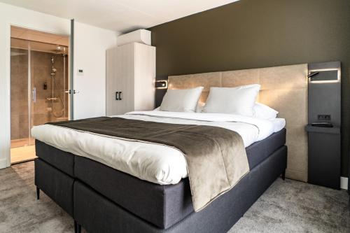 a bedroom with a large bed and a shower at Hotel Kogerstaete Texel in De Koog