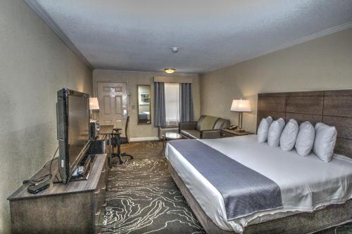 ゲインズビルにあるThe Guest Lodge Gainesvilleの大型ベッドとテレビが備わるホテルルームです。