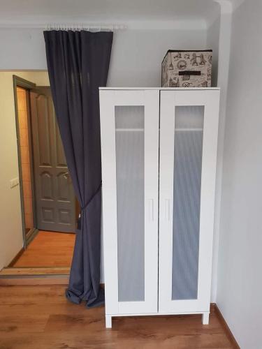 ein weißer Schrank in einem Zimmer mit einem Vorhang in der Unterkunft Karoso Apartment in Klaipėda