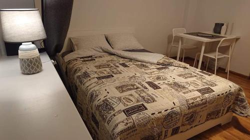 ein Schlafzimmer mit einem Bett mit einer Bettdecke und einem Tisch in der Unterkunft Karoso Apartment in Klaipėda