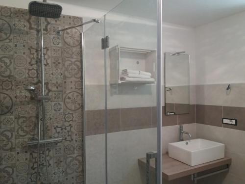 a bathroom with a sink and a glass shower at Il mestiere di vivere -casa vacanze- in Santo Stefano Belbo