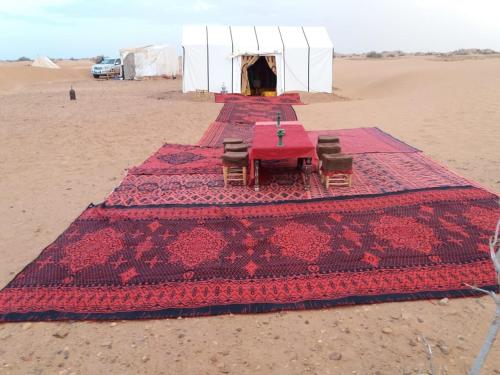 un grupo de mesas y sillas en el desierto en Erg Lihoudi Dunes & Bivouac, en Mhamid