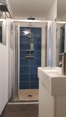 a bathroom with a shower with a blue wall at Le Rousseau Sarlat in Sarlat-la-Canéda