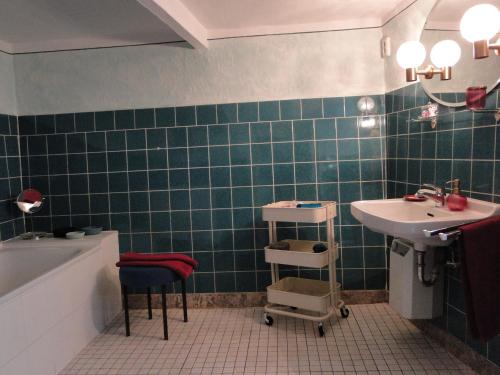 a green tiled bathroom with a sink and a tub at Altes Spitzhaus an der Goldroul in Senheim
