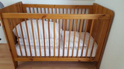 - un lit bébé en bois avec des draps blancs dans l'établissement Augustinushof 13, à Vrouwenpolder