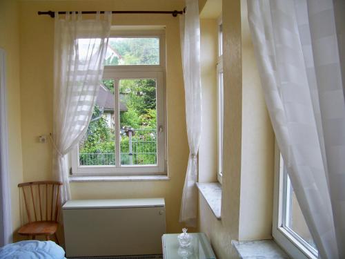 1 dormitorio con ventana, 1 cama y 1 silla en Villa - Sonnenberg, en Obersulm