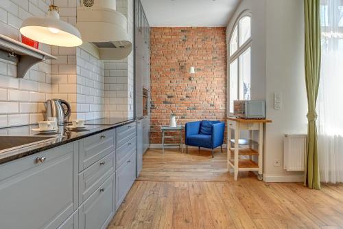 eine Küche mit weißen Schränken und einer Ziegelwand in der Unterkunft Lion Apartments - Scandi Love II in Sopot