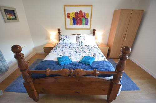 1 dormitorio con cama de madera y almohadas azules en Byron Cottage overlooking Loch Goil, en Lochgoilhead