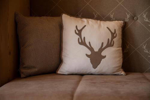 a pillow with deer antlers on it sitting on a couch at Dolomiti Lodge Alverà in Cortina dʼAmpezzo