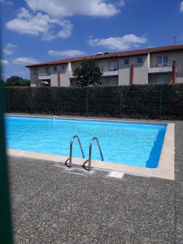 une grande piscine bleue avec 2 poignées en métal dans l'établissement Appartement Cosy proche Météo France et Airbus, à Toulouse