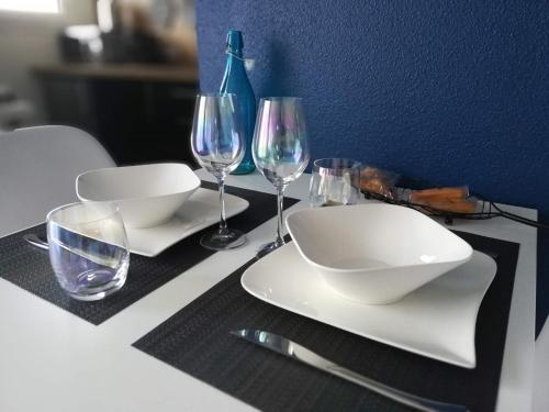 a table with white plates and wine glasses on it at Appartement Cosy proche Météo France et Airbus in Toulouse