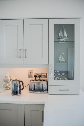 a kitchen with white cabinets and a toaster on a counter at Spectacular ocean views & minutes to Cliffs- Clahane Shore Lodge in Liscannor