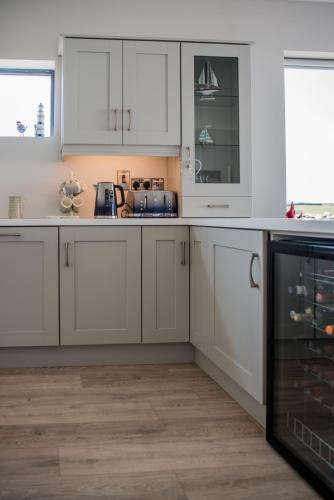 a kitchen with white cabinets and a wooden floor at Spectacular ocean views & minutes to Cliffs- Clahane Shore Lodge in Liscannor