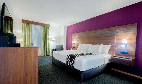 a hotel room with a large bed and a purple wall at La Quinta by Wyndham San Jose Chiapa Puebla in San José Chiapa
