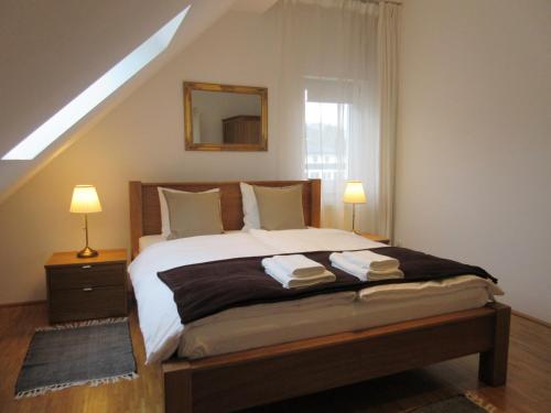 a bedroom with a bed with two lamps and a window at Home Apartments in Salzburg