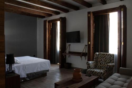 a bedroom with a bed and a chair and a tv at Hotel Diana in Puebla