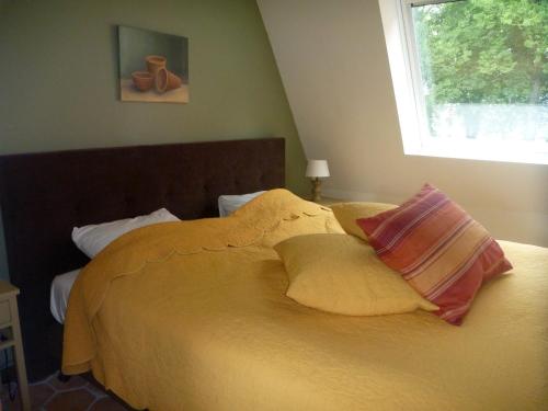 a yellow bed with two pillows and a window at Hotelsuites Ambrosijn in Schiermonnikoog
