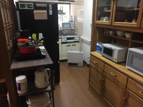 a small kitchen with a stove and a microwave at Guest House Hinode in Takayama