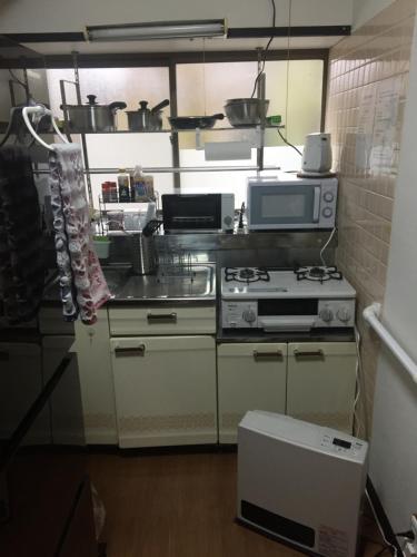 a kitchen with a stove and a microwave at Guest House Hinode in Takayama