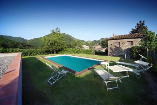 una piscina en un patio con sillas y una casa en Casa Patrizia, en Borgo a Mozzano