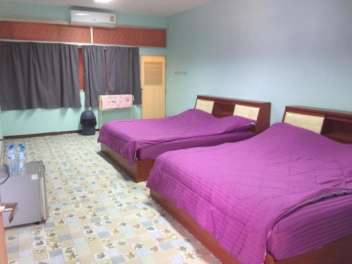 two beds in a room with purple sheets at Navy Home Sattahib in Sattahip