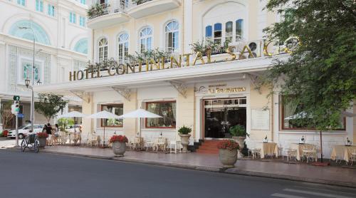 een hotel met tafels en stoelen voor een gebouw bij Hotel Continental Saigon in Ho Chi Minh-stad