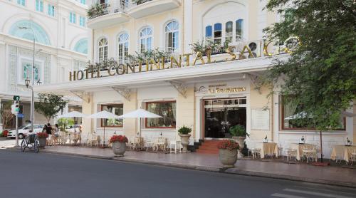 um hotel com mesas e cadeiras em frente a um edifício em Hotel Continental Saigon em Cidade de Ho Chi Minh