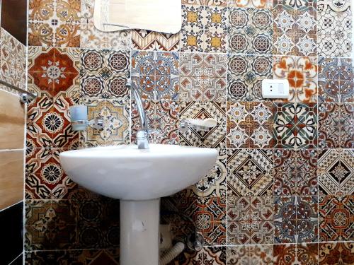 uma casa de banho com um lavatório e uma parede de azulejos em Arabian Nights Pyramids Guesthouse no Cairo