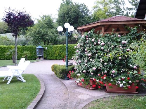 a garden with a gazebo and a white bench and flowers at Bed And Breakfast Olimpia in San Salvatore Monferrato
