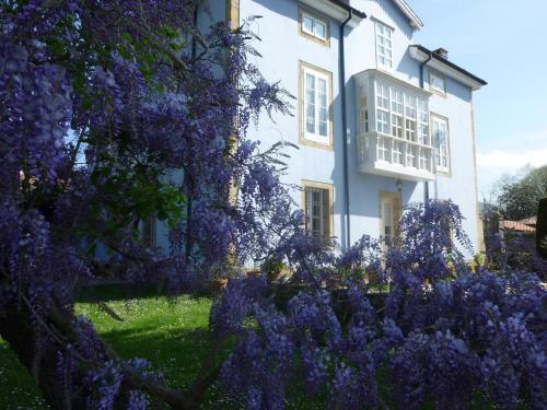 a house with purple flowers in front of it at La Casona Azul, espectacular palacio indiano in Corvera