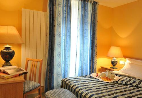a bedroom with a bed with a table and a window at Logis Hotel Le Continental in Châteauroux