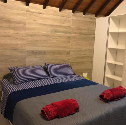 1 dormitorio con 1 cama con 2 almohadas rojas en Bangalô luxo Carneiros Beach Resort, en Praia dos Carneiros