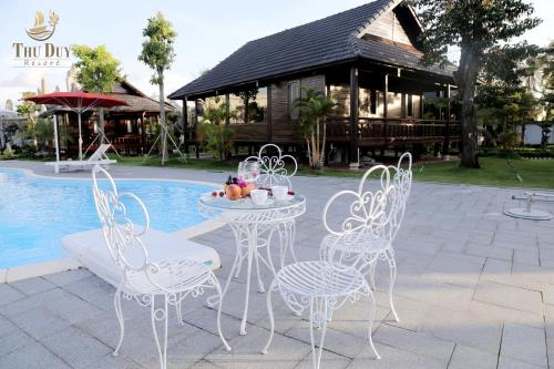 stół i krzesła przed basenem w obiekcie THƯ DUY Resort w mieście Cà Mau