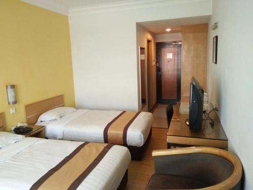 TuaranにあるTang Dynasty Lodge Tuaranのベッド2台、薄型テレビが備わるホテルルームです。
