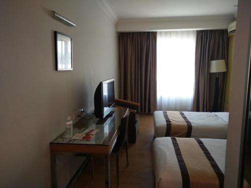 TuaranにあるTang Dynasty Lodge Tuaranのベッド2台、デスク、テレビが備わるホテルルームです。