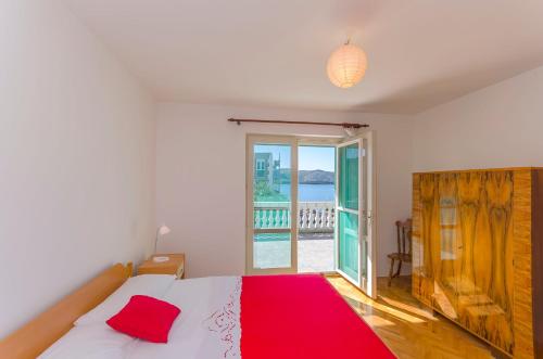 a bedroom with a bed with a red blanket and a window at House Marina in Zaboric