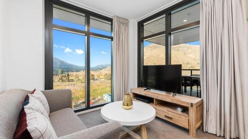 a living room with a television and large windows at Remarkables Garden 406 - Top Corner Unit - Super Convenient in Queenstown