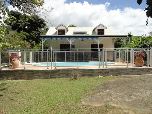 a house with a fence around a swimming pool at Villa Les Gallières in Pointe-Noire