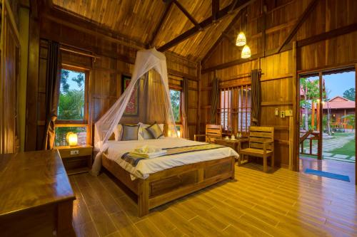 une chambre avec un lit dans une pièce en bois dans l'établissement Island Lodge, à Duong Dong