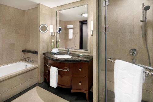 a bathroom with a sink and a tub and a mirror at Shangri-La Jakarta in Jakarta