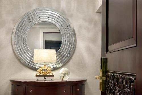 a mirror on a wall above a table with a lamp at Shangri-La Jakarta in Jakarta