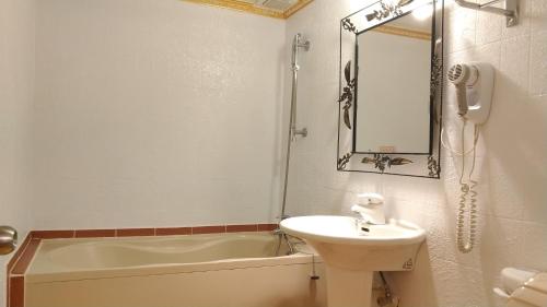 a bathroom with a sink and a tub and a mirror at Aloha Hotel in Keelung