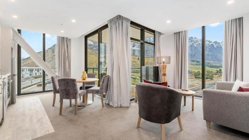 a living room with a table and chairs and windows at Remarkables Garden Apartment 305 in Queenstown