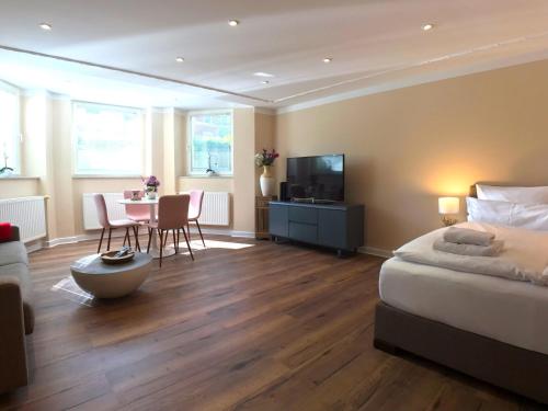 een slaapkamer met een bed, een tafel en een televisie bij Amaroo - Apartments Potsdam “Alexandrowka” in Potsdam
