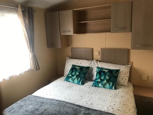 a small bedroom with a bed with blue pillows at Poppy at Oakdene Forest Park in Ringwood